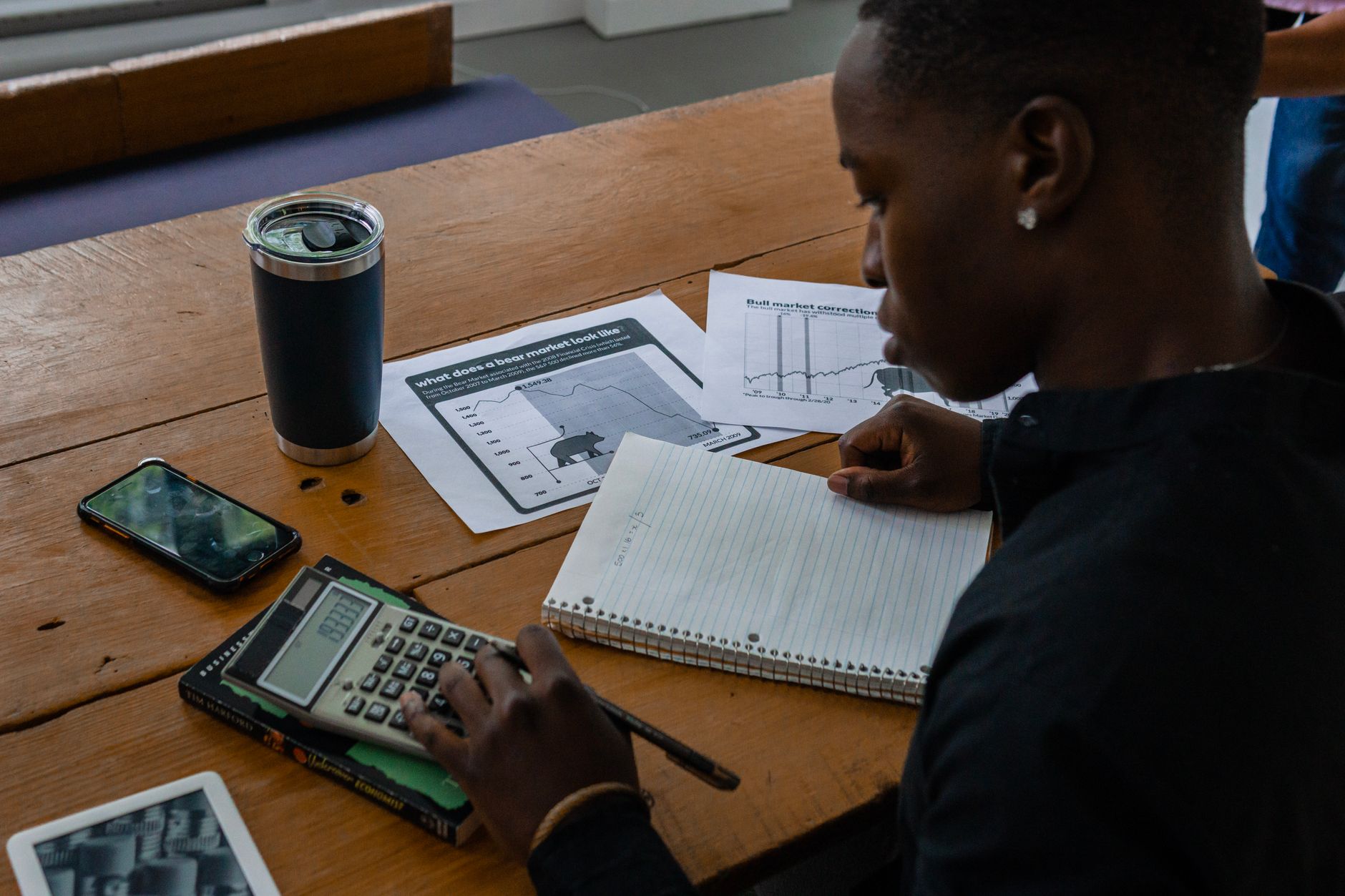Self-employed small business owner reviewing bank statements and financial documents at a desk