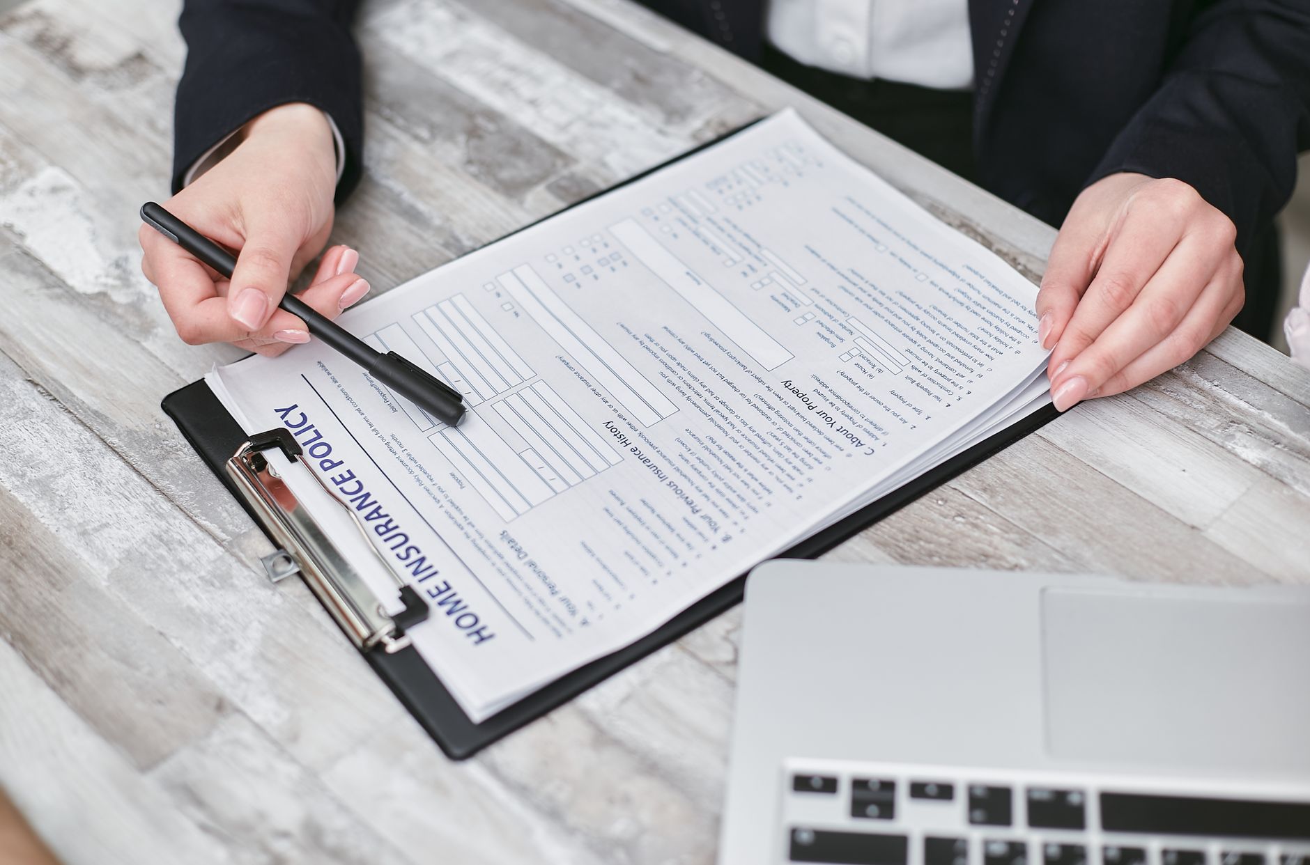 Homeowner reviewing a homeowners insurance policy next to a house model and mortgage paperwork